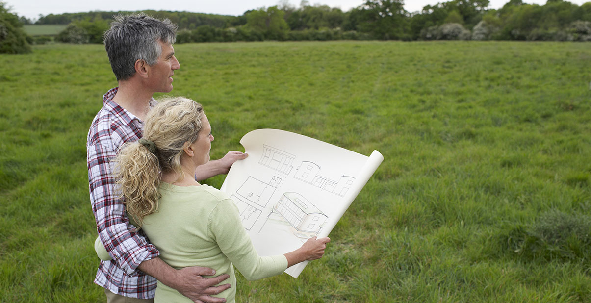 Couple looks at house plans on empty lot